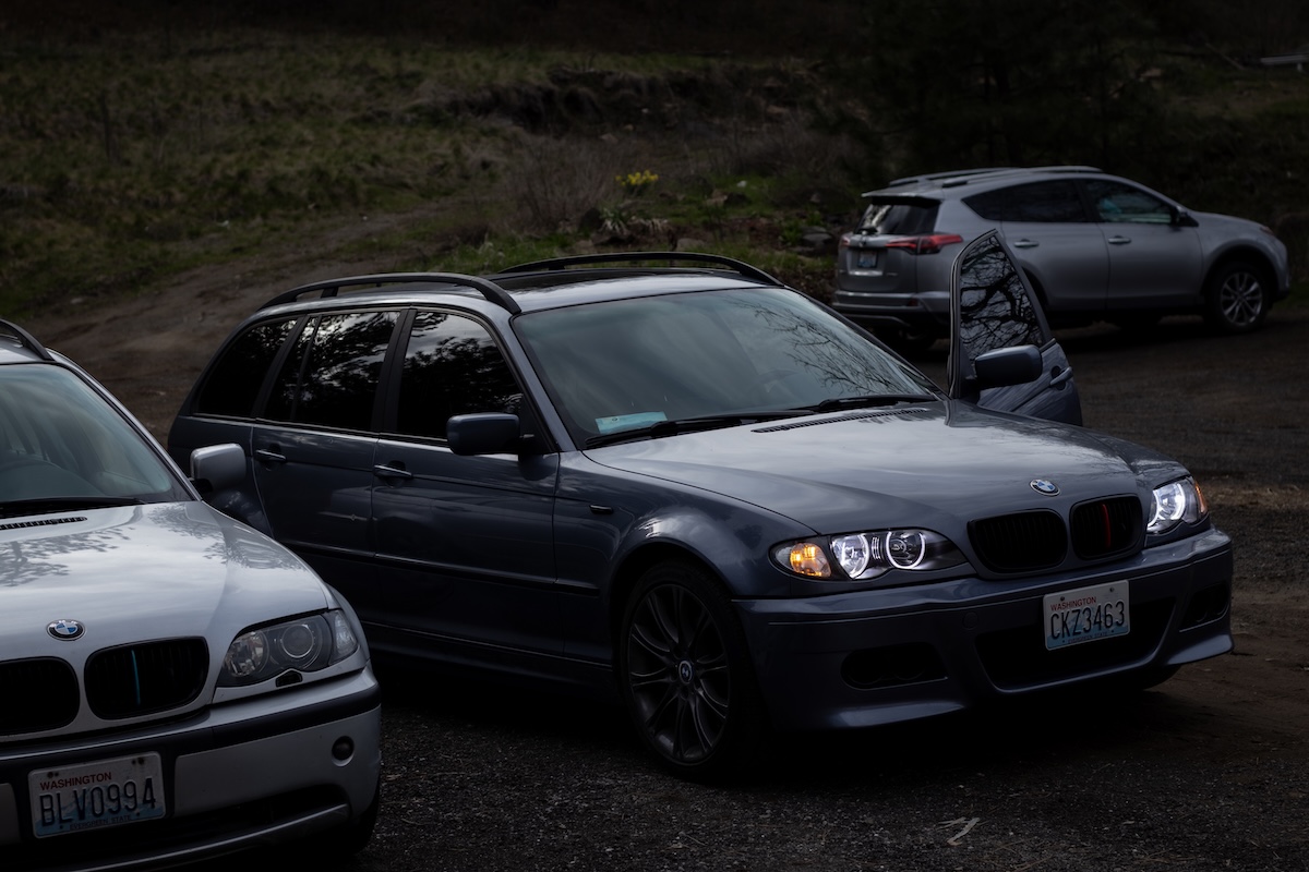 BMW E46 parked in dirt lot with multiple cars
